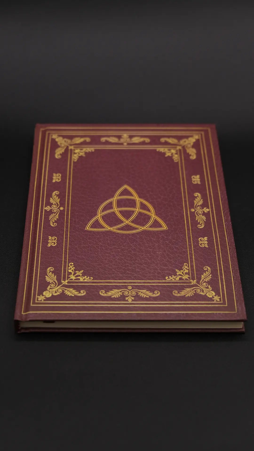 A red diary with beautiful ornamentation over the black background.