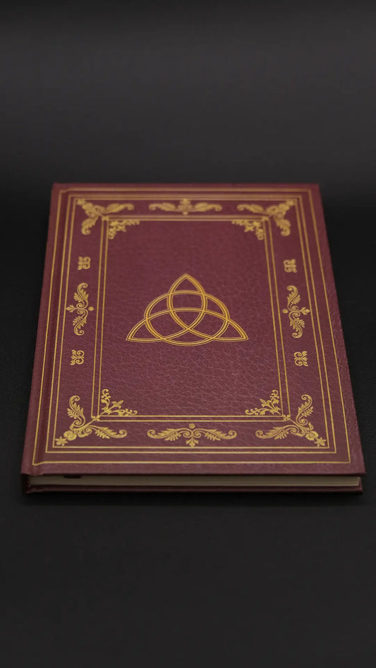 A red diary with beautiful ornamentation over the black background.