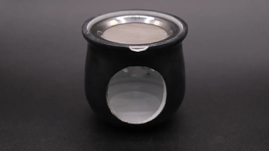 Black incense burner in steatite with a pentacle over a black background,  rear view