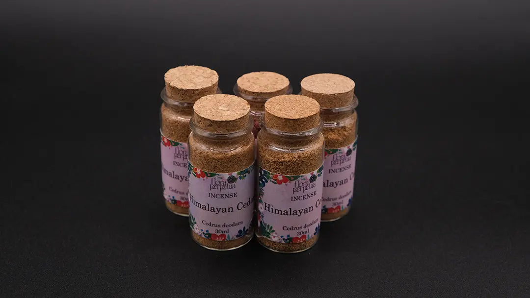Five Himalayan Cedar Herb incense bottles over the black background.