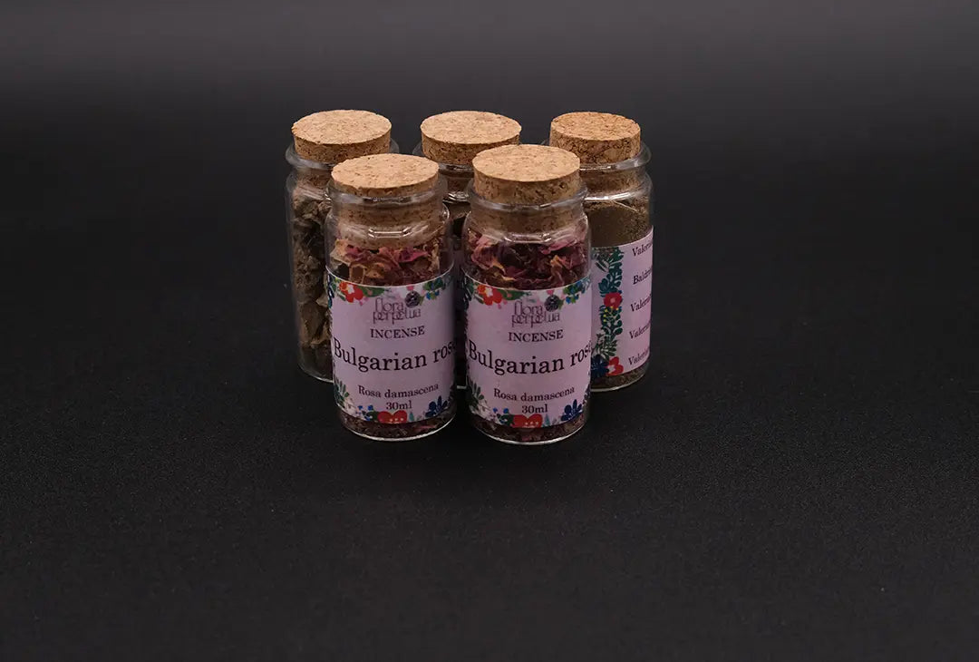 Set of 5 bottles of bulgarian rose incense placed over a black background