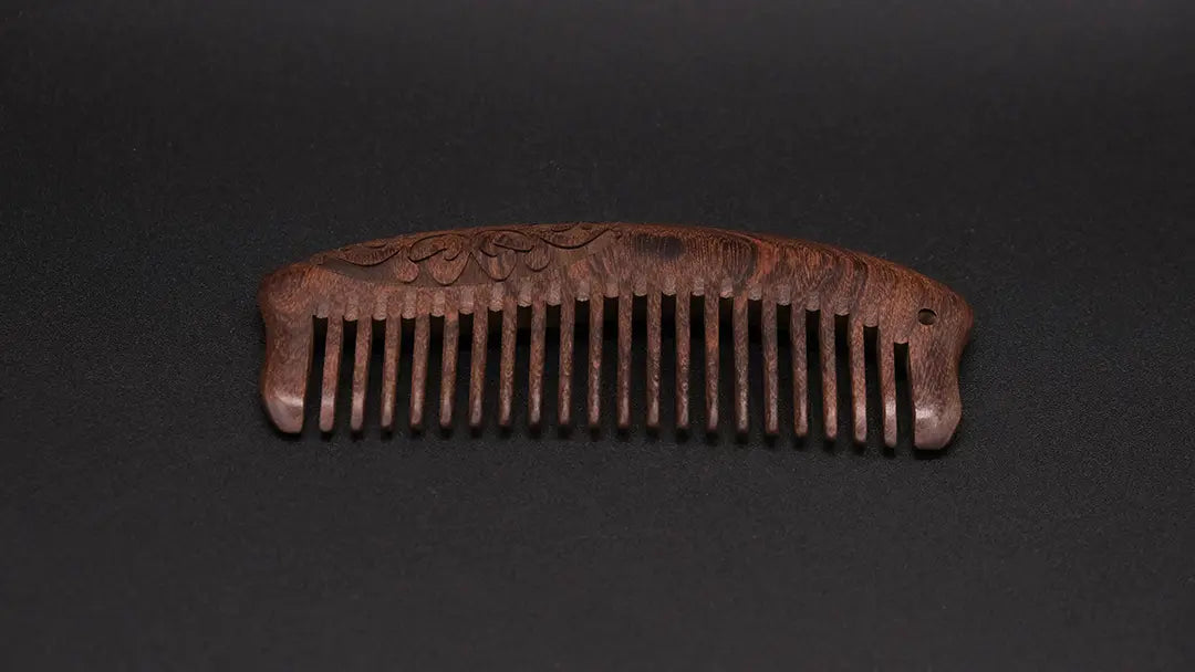 Wooden ornamented eco friendly comb on the black background.