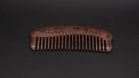 Wooden ornamented eco friendly comb on the black background.