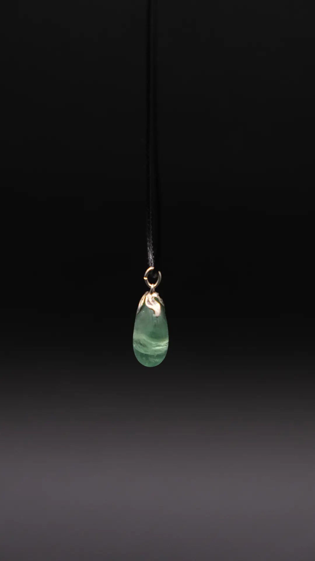A green aventurine pendant over a black background
