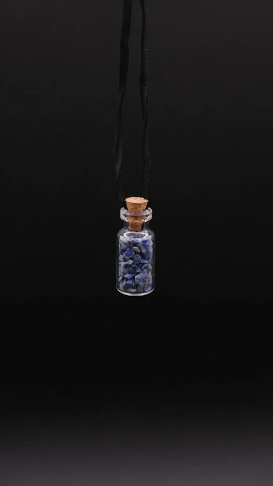 pendant made with a little glass bottle filled with lapis lazuli shards placed over a black background