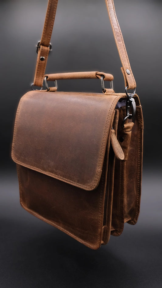 Shoulder bag in light brown leather over the black background.