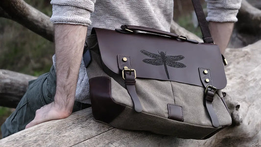 A man is wearing a brown leather satchel engraved with a dragonfly drawn