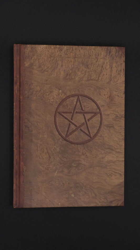 Light brown Journal with the pentacle symbol over the black background.