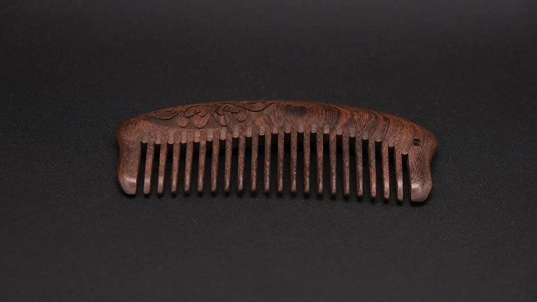 Wooden ornamented eco friendly comb on the black background.