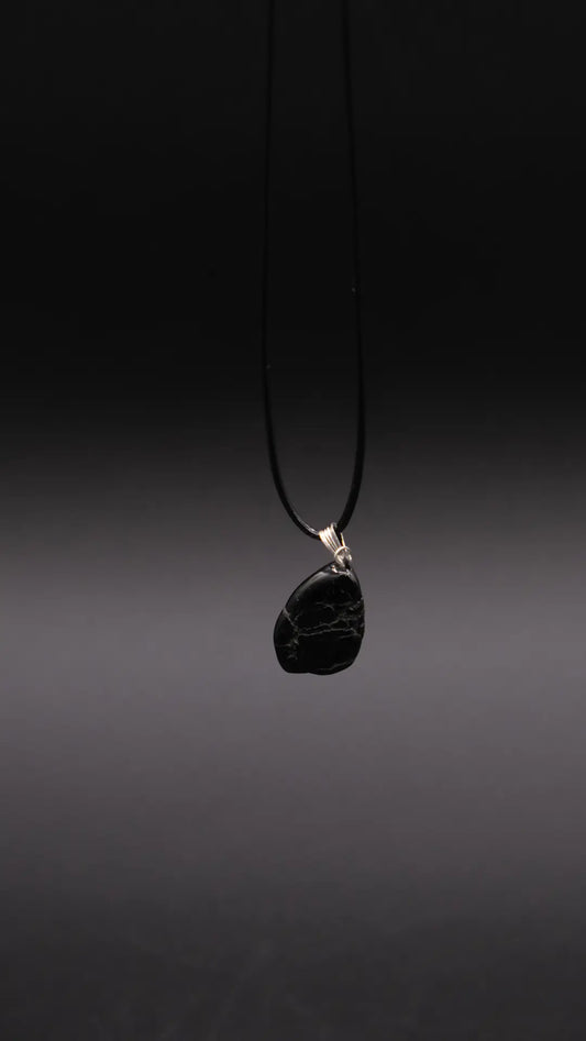 a black pendant in onyx stone over a black background