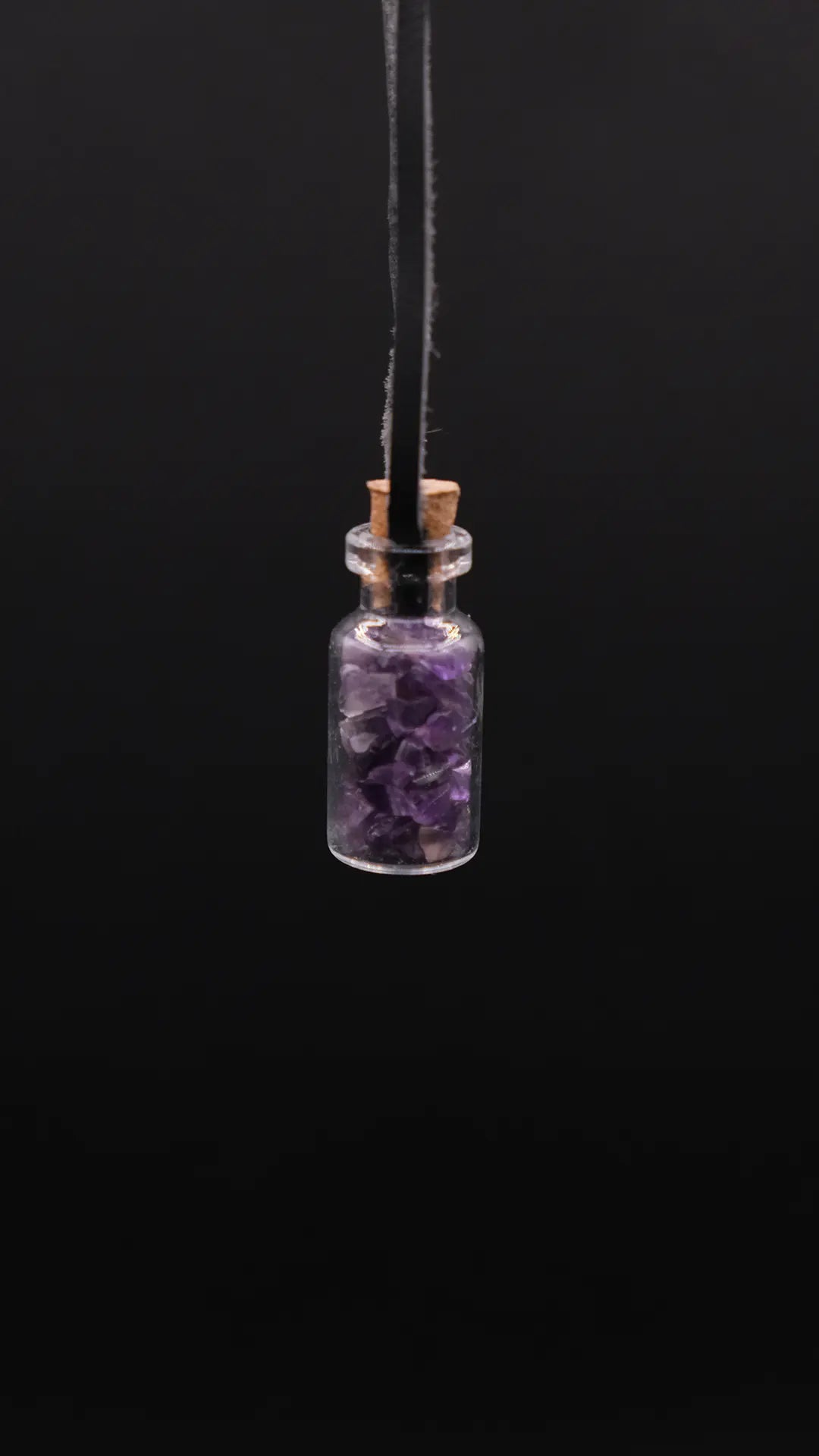 pendant made with a little glass bottle filled with amethyst shards over a black background