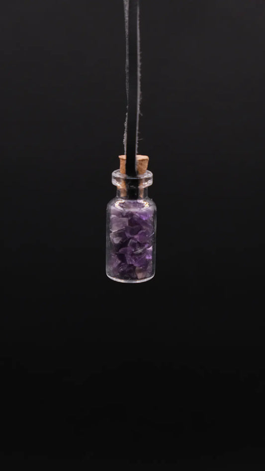 pendant made with a little glass bottle filled with amethyst shards over a black background