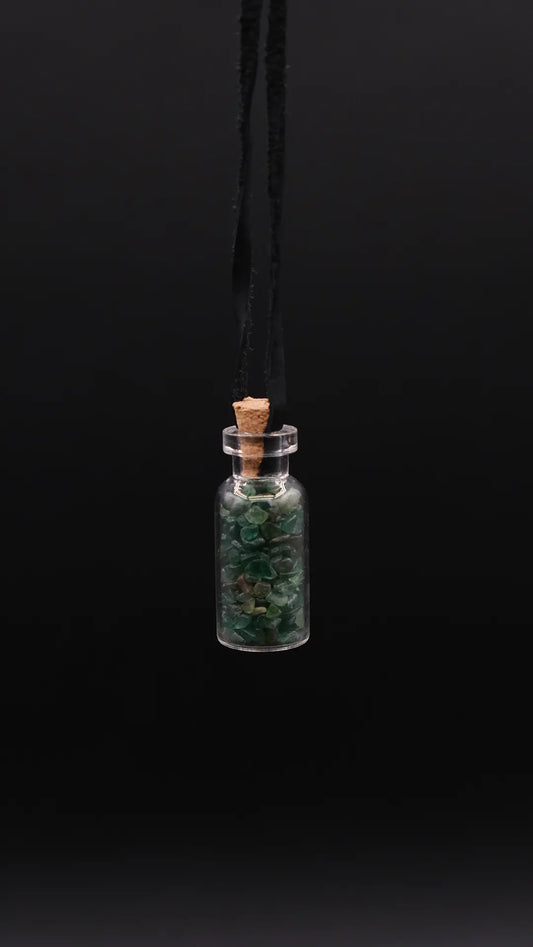 pendant made with a little glass bottle filled with aventurine shards over a black background