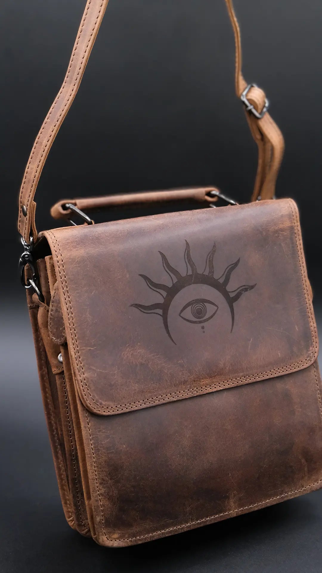 A Shoulder bag in light brown leather with solar crown symbol engraved on the black background.